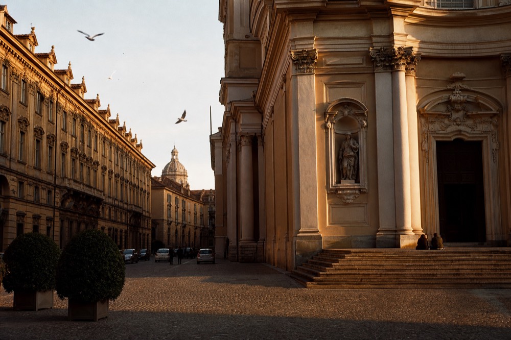 A grand Turin piazza framed by baroque facades in late afternoon light.