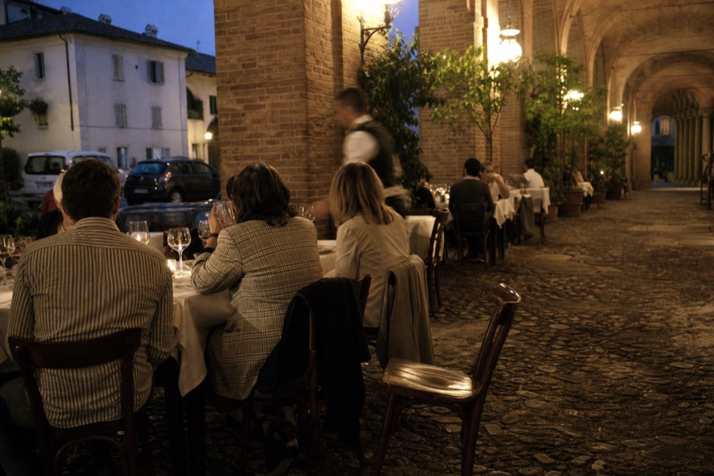 An evening table set for dinner in a Turin arcaded square.