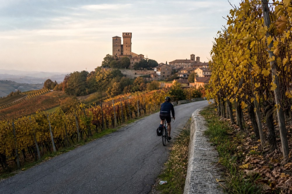Cyclist on an e-bike riding past Barolo vineyards in autumn.