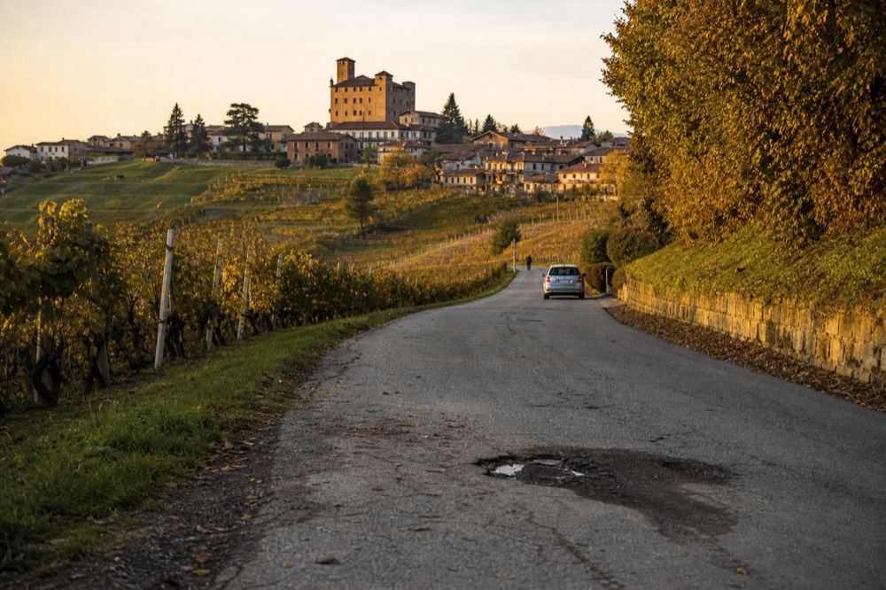 Ridge road through Barolo vineyards with hilltop village.