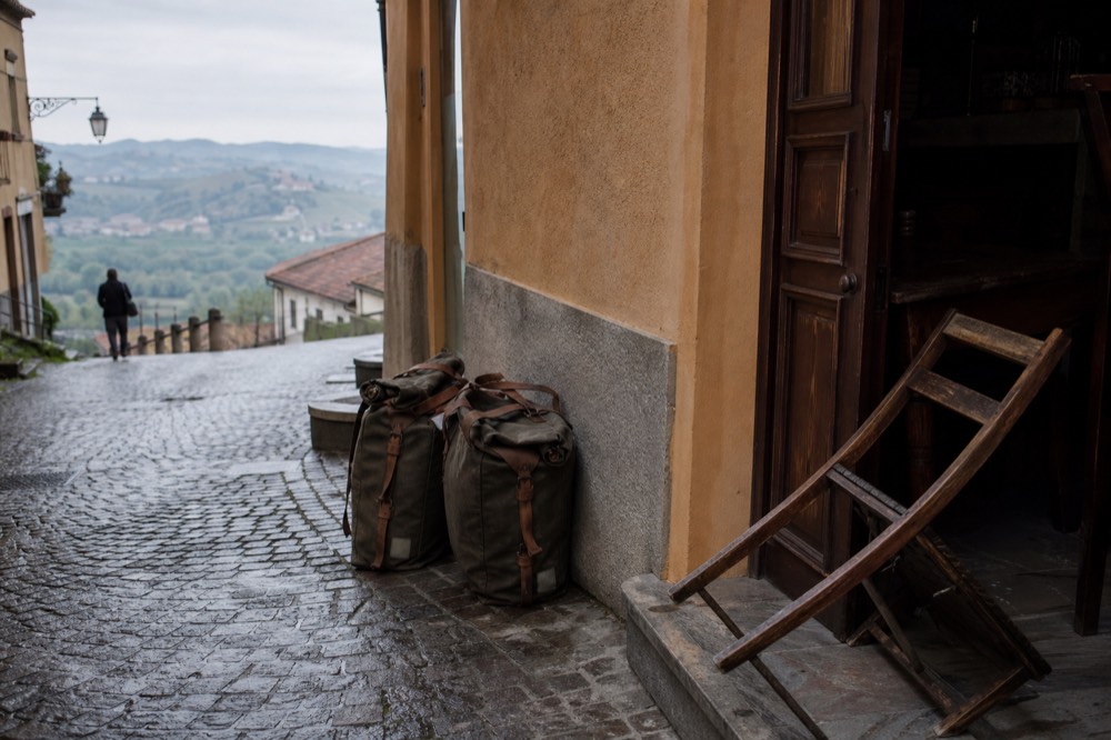 Packed panniers on a bicycle outside a stone village building in the Langhe.