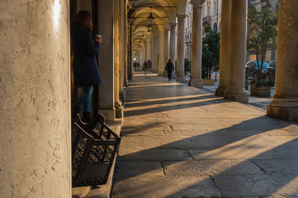 Turin arcade street with morning light through the arches.