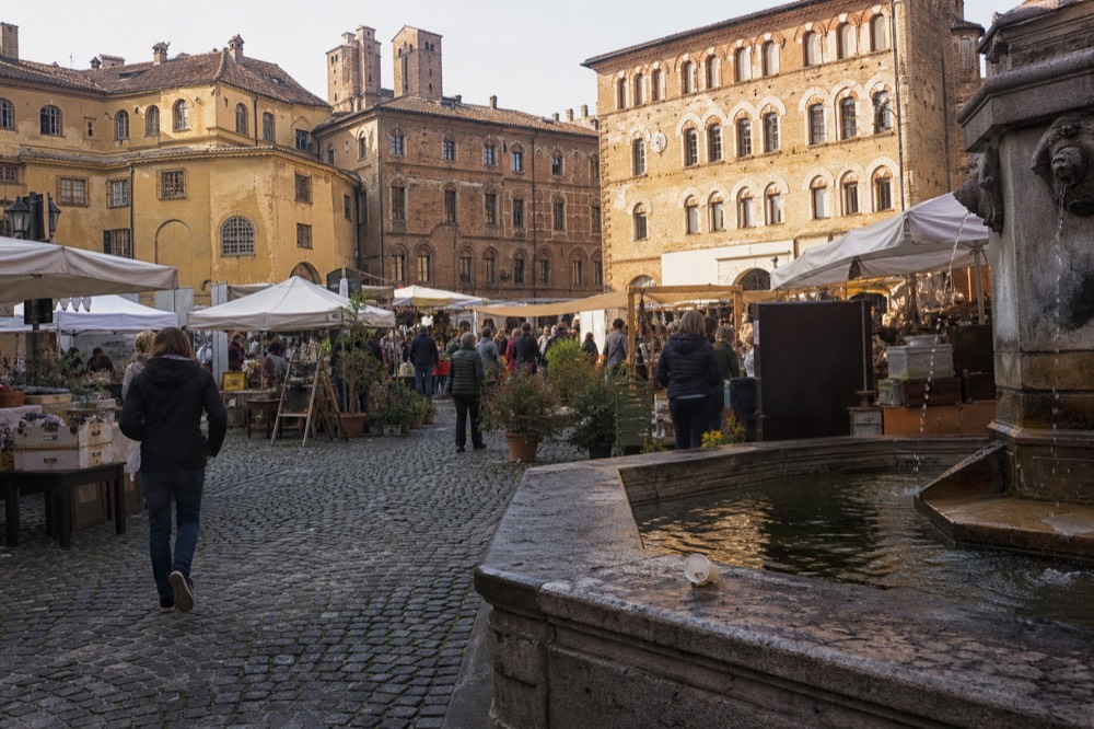 Alba historic centre with market stalls and crowds in a piazza during the truffle fair.
