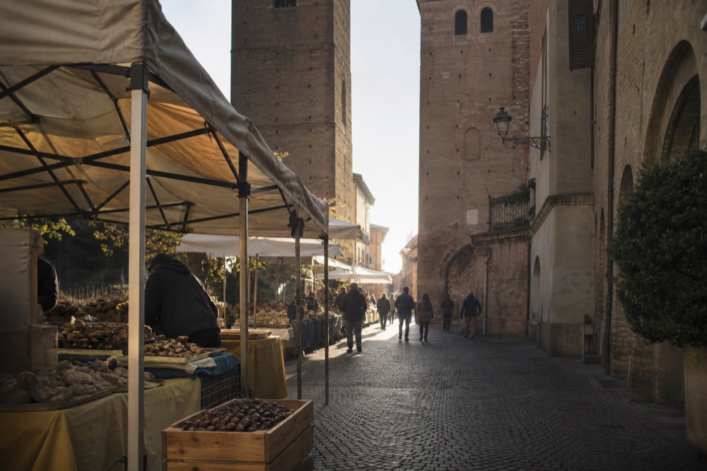 Alba historic centre street with market stalls and towers above.
